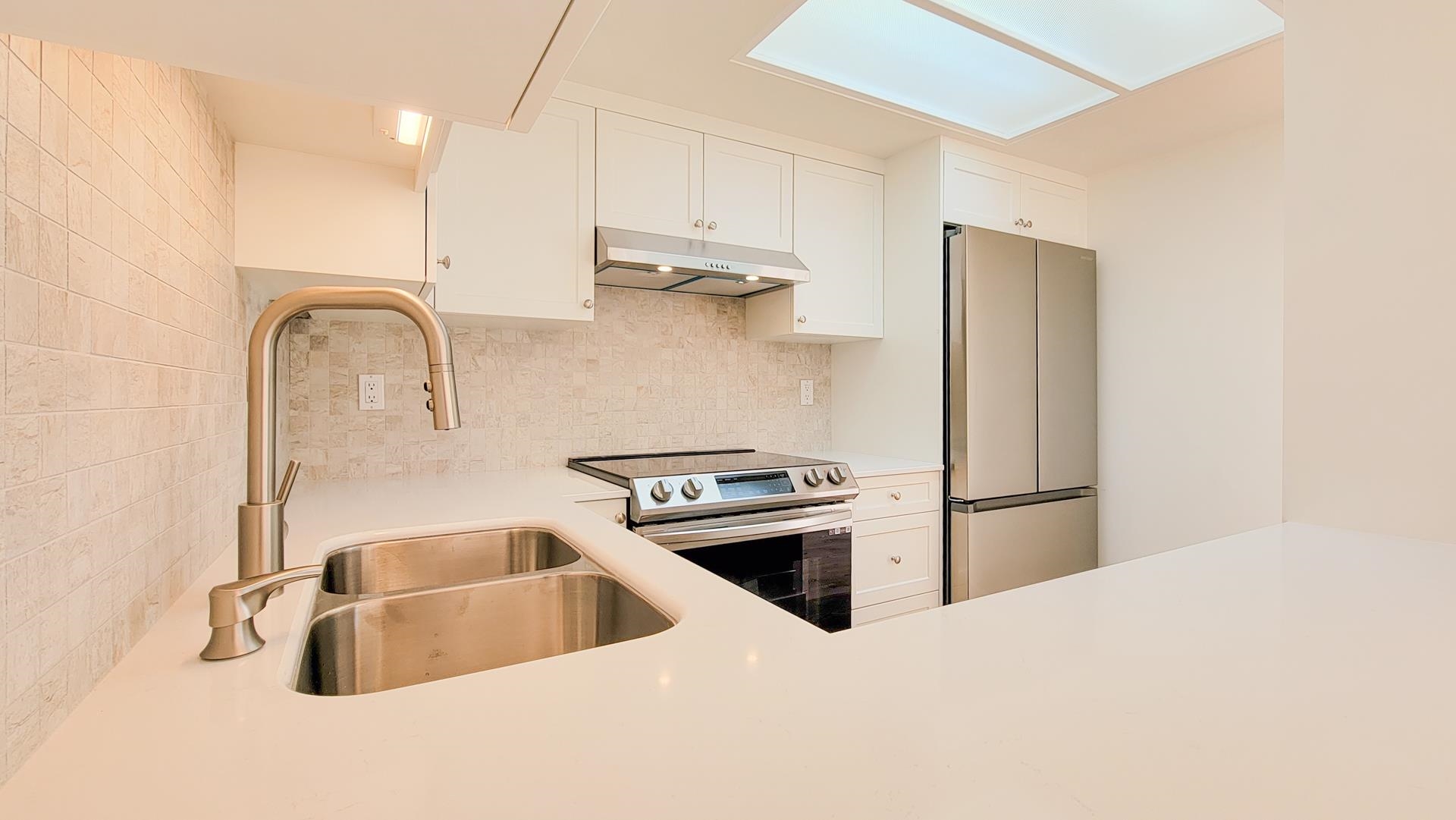 The Silestone counters are white with traces of grey which enhance the tile backsplash which is a mixture of greys.